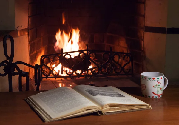 Man and woman in warm socks near the fireplace. Cup with a hot drink. Heart.