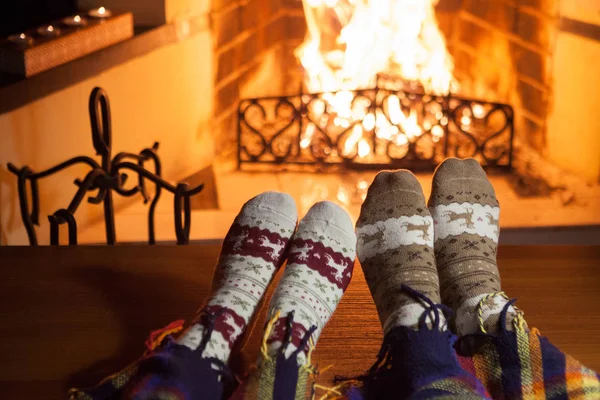 Man and woman in warm socks near the fireplace. Cup with a hot drink. Heart.