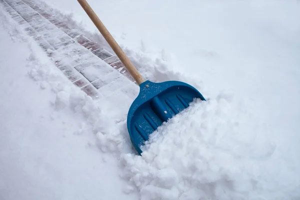 Cleaning snow with shovel in winter day