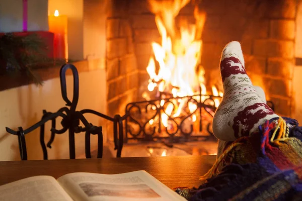 Man and woman in warm socks near the fireplace. Cup with a hot drink. Heart.