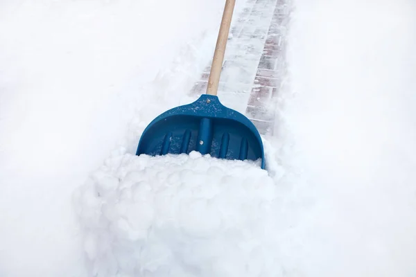 Cleaning snow with shovel in winter day