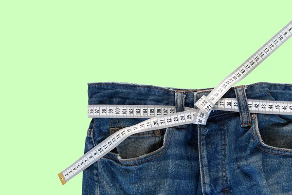 Yeşil Arka Planda Mezurası Olan Kot Pantolonlar Kilo Verme Konsepti — Stok fotoğraf