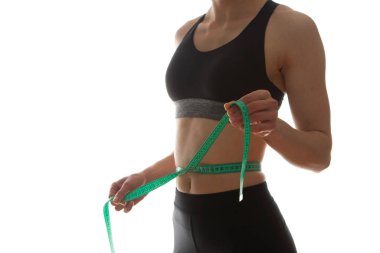 Zayıf, genç bir kadın, ince belini ölçüyor.