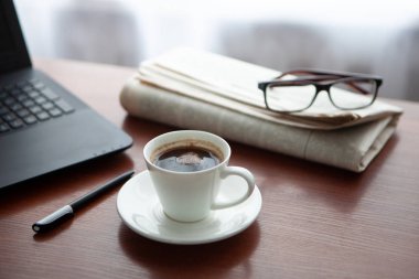 Masada bilgisayar olan bir gazete. Kahve molası.