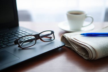 Masada bilgisayar olan bir gazete. Kahve molası.