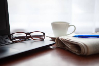 Masada bilgisayar olan bir gazete. Kahve molası.