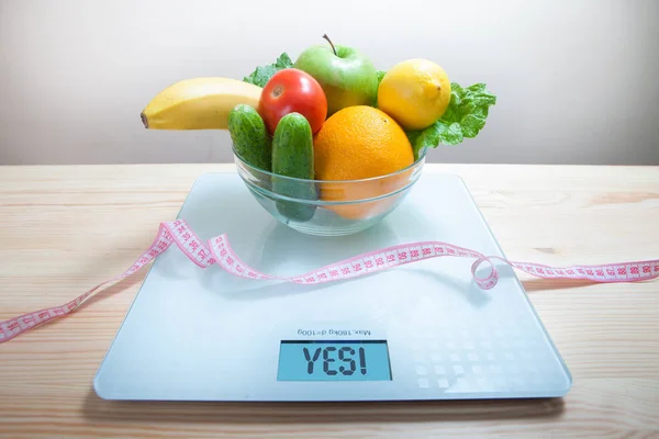 Healthy diet, fitness and weight loss concept, fruits, vegetables on the table. Girl with measuring tape.