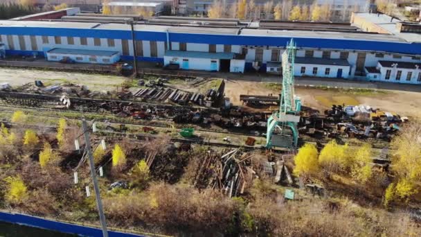 Aerial flight over warehouse of scrap metal. Crane on rails loads metal pieces — Stock Video