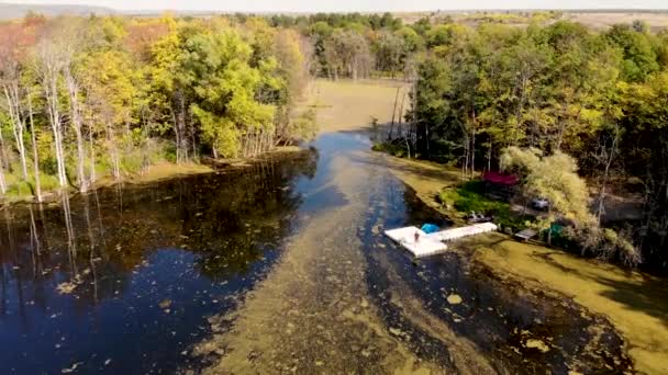 Vuelo aéreo sobre un lago pantanoso, en cuya orilla un pescador captura un pez — Vídeo de stock