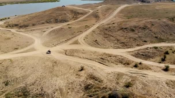 Motorkář projíždí po opuštěné silnici na břeh jezera setkat se s přáteli — Stock video