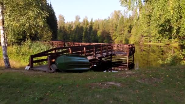 Volo aereo su un ponte di legno sulla riva di un piccolo lago boschivo — Video Stock