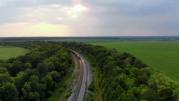 Εναέρια λήψη εμπορευματικής αμαξοστοιχίας που ταξιδεύει σιδηροδρομικώς. Που λαμβάνονται με drone στο ηλιοβασίλεμα — Αρχείο Βίντεο
