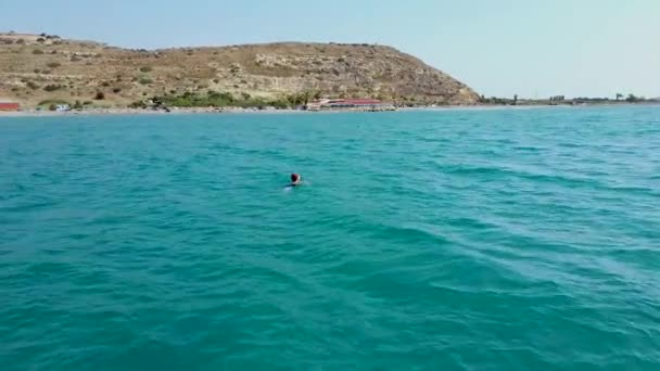 Vista aérea de un dron de una joven sola chica flotando en el mar transparente — Vídeo de stock