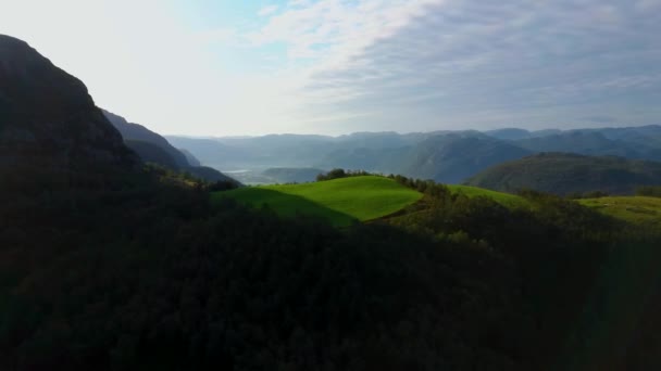 Drohnenflug vorwärts zur grünen Wiese auf einem Hügel. Aufgenommen bei Sonnenuntergang in Norwegen Videoclip
