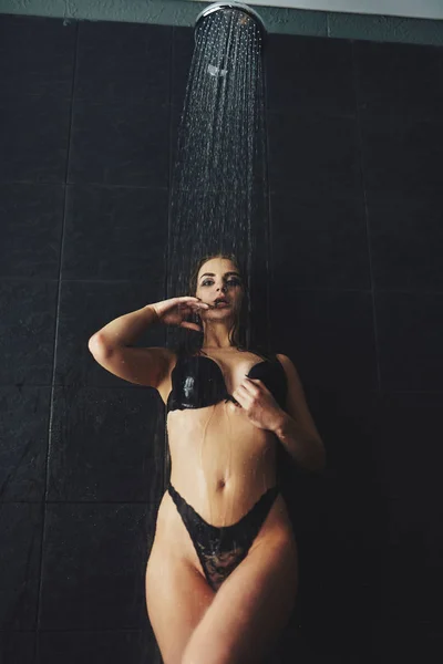 En vacker flicka står i duschen. Våt fotografering — Stockfoto