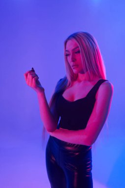 Pembe arka plan üzerinde iskemlede çekici sarışın kadın