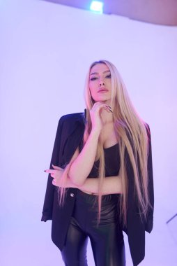 Pembe arka planda siyah deri pantolonlu güzel bir kadın.