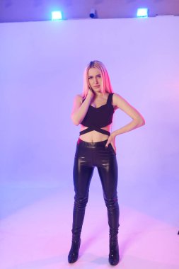 Pembe arka planda siyah deri pantolonlu güzel bir kadın.