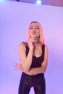 Pembe arka planda siyah deri pantolonlu güzel bir kadın.