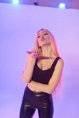 Pembe arka planda siyah deri pantolonlu güzel bir kadın.