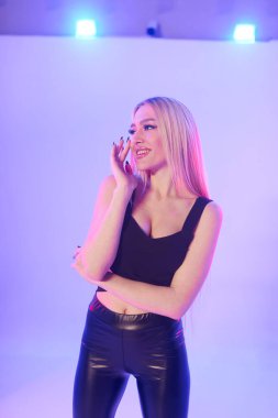 Pembe arka planda siyah deri pantolonlu güzel bir kadın.