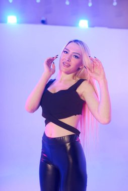 Pembe arka planda siyah deri pantolonlu güzel bir kadın.