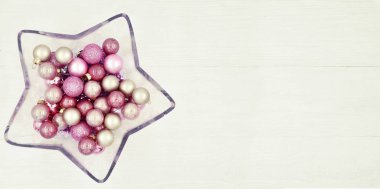 Tahta beyaz arka planda Noel topları olan yıldız şeklinde cam vazo..