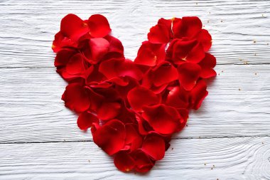 Beyaz ahşap arka planda kalp şeklinde kırmızı gül yaprakları serilmişti. Sevgililer Günü arkaplanı.