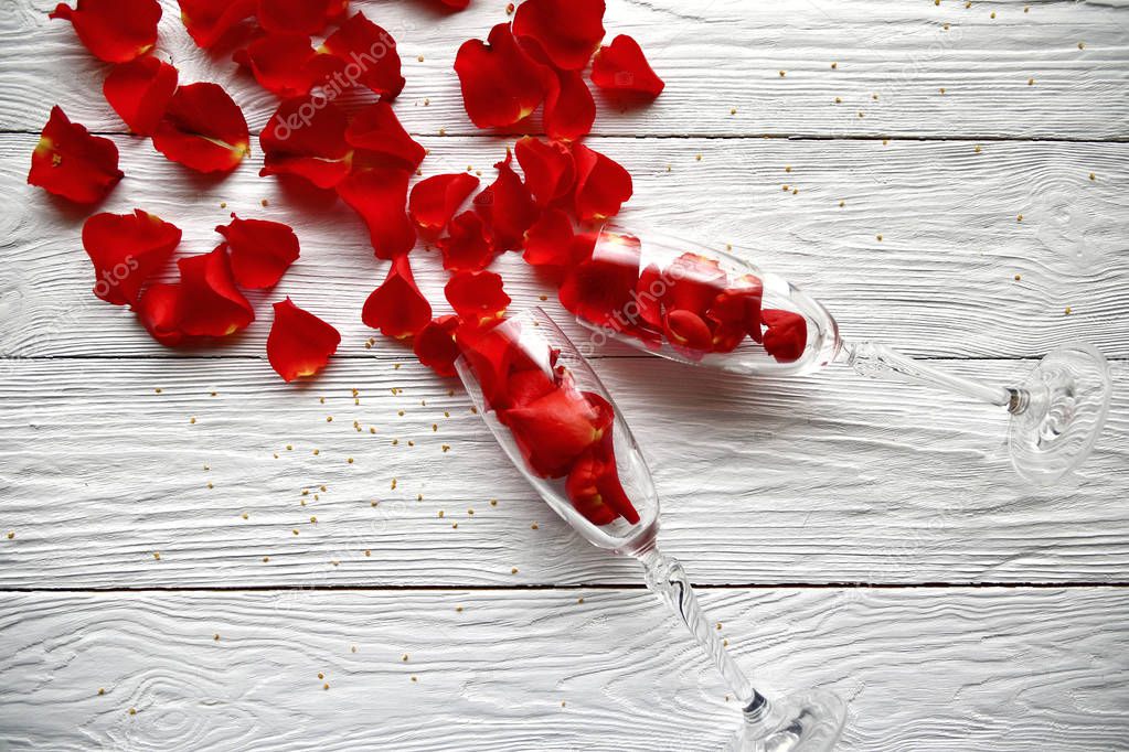 Red rose petals spilled out of wine glasses. St. Valentine's Day background.