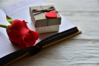 Kırmızı gül ve kitabın üzerinde bir hediye kutusu var. Sevgililer Günü arkaplanı.