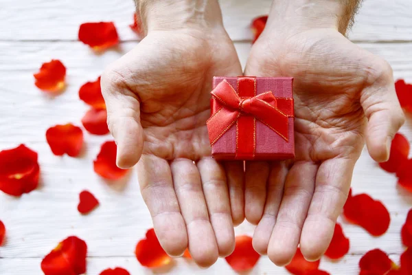 Manos Masculinas Con Una Caja Regalo Sobre Fondo Pétalos Rosa — Foto de Stock