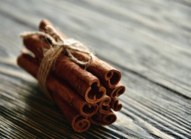 Tarçın, iple bağlanmış koyu ahşap bir yüzeye yapışır. Yakın plan. Yan görüş. Doğal ışık.