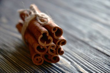 Tarçın, iple bağlanmış koyu ahşap bir yüzeye yapışır. Yakın plan. Yan görüş. Doğal ışık.