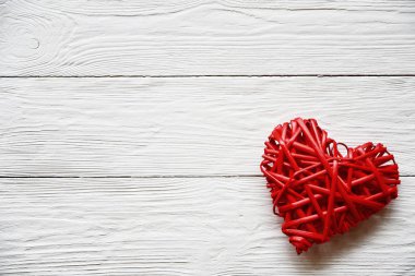 Big red rattan heart on a white wooden background. Close-up. Top view. St. Valentine's Day background.