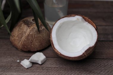 Tahta bir masada iki hindistan cevizi ve hindistan cevizi suyu dolu bir bardak.