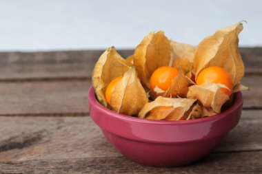 Tahta bir masadaki kasede fizsalis.