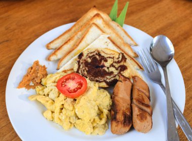 Omlet, tavuk sosis ve beyaz tabakta domatesli ekmek sabah kahvaltısı ve Amerikan kahvaltısı için hazırlandı.