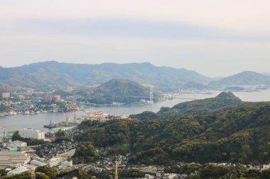Güneşli bir günde Nagasaki şehrinin, mavi gökyüzünün ve dağların olduğu İnasa Dağı 'nın manzarası.
