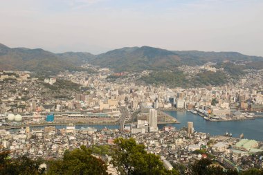 Güneşli bir günde Nagasaki şehrinin, mavi gökyüzünün ve dağların olduğu İnasa Dağı 'nın manzarası.
