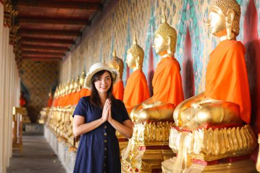 Bangkok, Tayland 'daki Wat Arun' da Buda 'ya dua eden mavi şapkalı güzel bir Asyalı kız. Wat Arun Tayland 'ın ünlü bir turizm merkezidir. Seyahat kavramı
