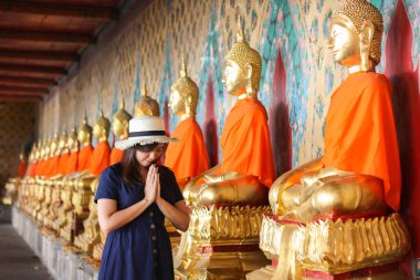 Bangkok, Tayland 'daki Wat Arun' da Buda 'ya dua eden mavi şapkalı güzel bir Asyalı kız. Wat Arun Tayland 'ın ünlü bir turizm merkezidir. Seyahat kavramı