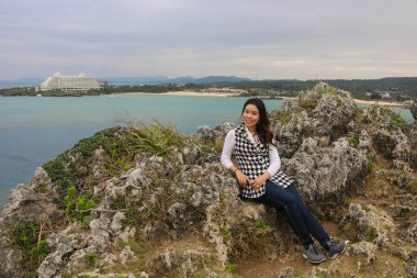 Japonya, Okinawa 'daki kayalıklarda poz veren Asyalı kadın.