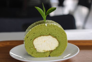 Yeşil çay patatesli kek üzerine yeşil çay yaprağı, beyaz tabakta..