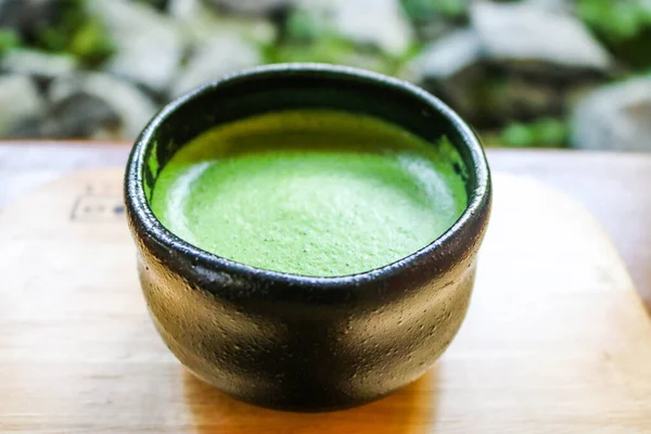 Matcha green tea in ceramic black cup on wooden plate, Japanese matcha tea is beverage of japanese