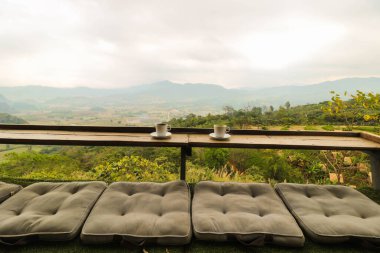 Ahşap balkonda iki kahve fincanı ve sabahleyin Tayland 'da manzara dağlı yastıklar.