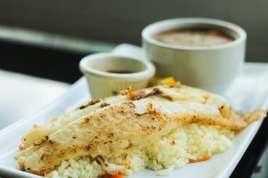 Izgara Pangasius fileto, pilav ve patates püresi, deniz ürünleri sosuyla servis ediliyor.