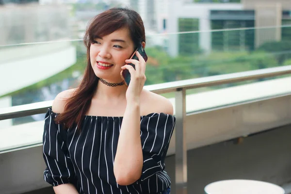 Asian girl wears black off shoulder top and talking on the mobile phone with her boyfriend, Telephone conversations.