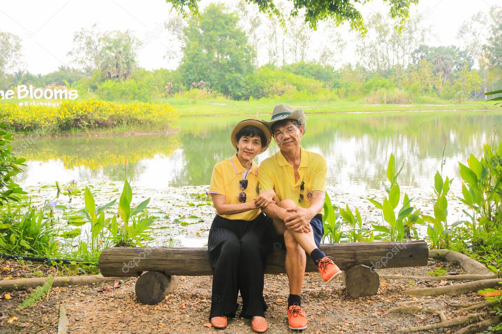 Romantic senior couple sitting on wooden bench in the park for relaxing