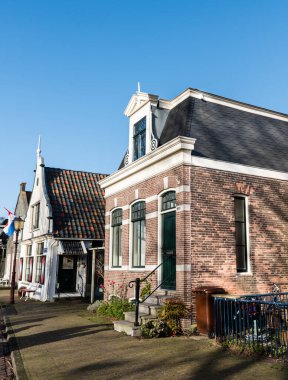 Amsterdam Holland, 20 Ocak 2020, Amsterdam North. Güneşli bir sonbaharda güneşli bir günde oturmak için ön cephenin önünde klasik evler, çiçekler ve banklar olan küçük bir sokak.
