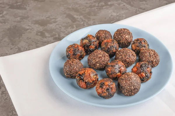 Çeşitli ev yapımı vegan trüf mantarları veya kurutulmuş kayısı ve finaki, badem, muz ve kakao, koyu çikolata ve fındık yağı gibi gri arka planda bulunan enerji topları